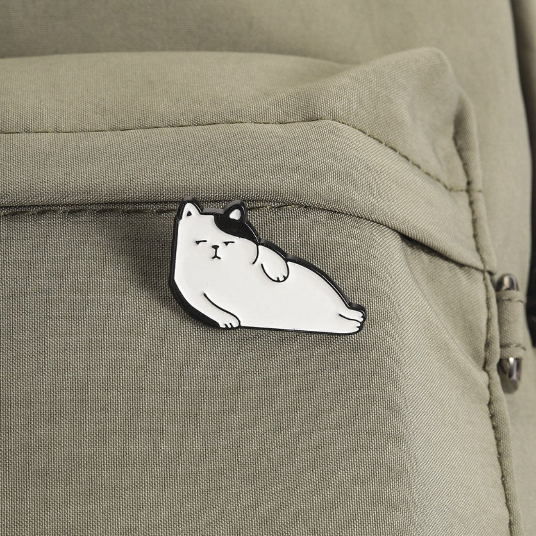 Pinori Lazy Cat Lounge enamel pin attached to fabric, showcasing size and design on clothing