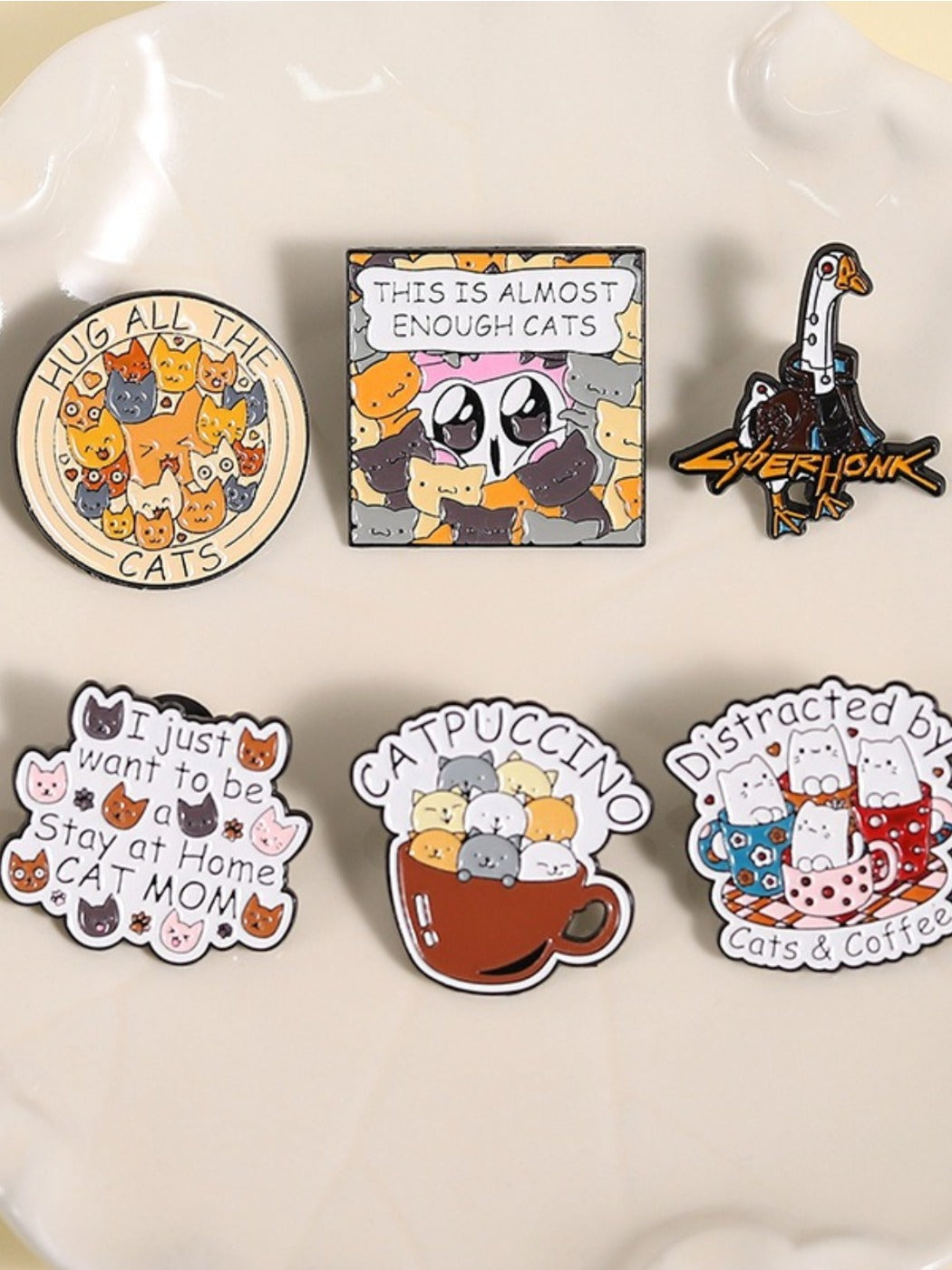 Close-up of the Pinori round metal pin showing detailed cat illustrations