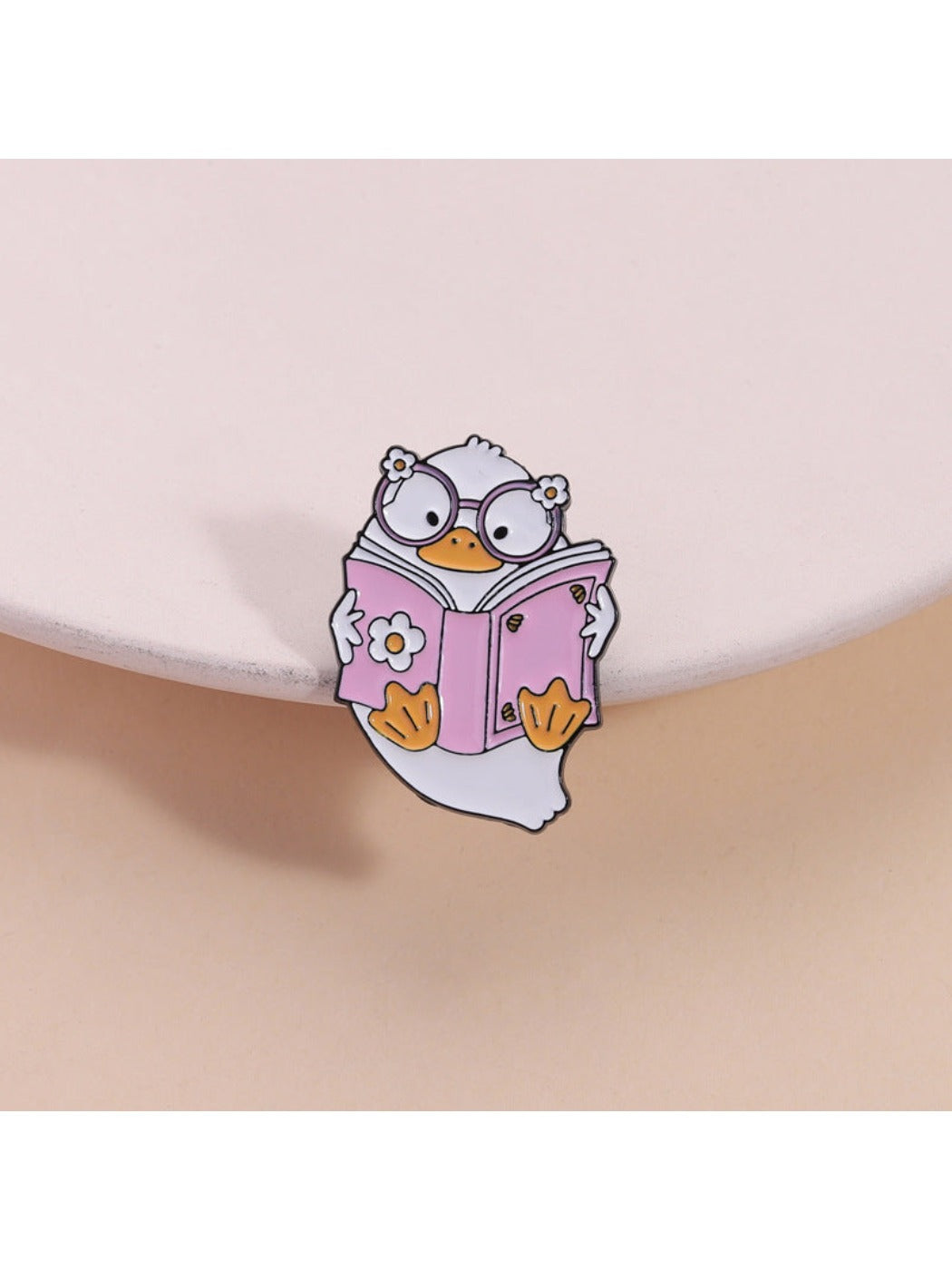 Pinori pink reading book brooch featuring a cute duck design on a white background