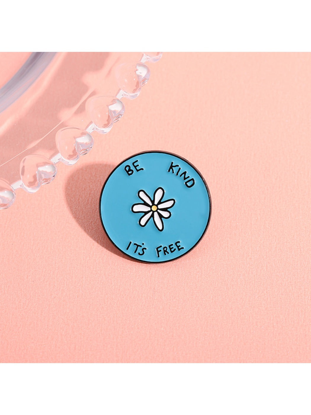 Close-up of Pinori blue round brooch with white flower and alphabet design