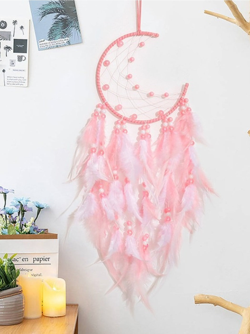 Close-up of pink feathers hanging from the moon shaped dream catcher