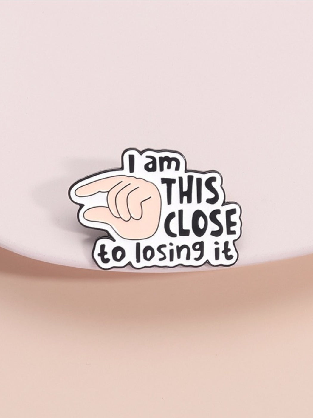 Pinori pin badge with 'I Will Close It' English letter design and finger illustration