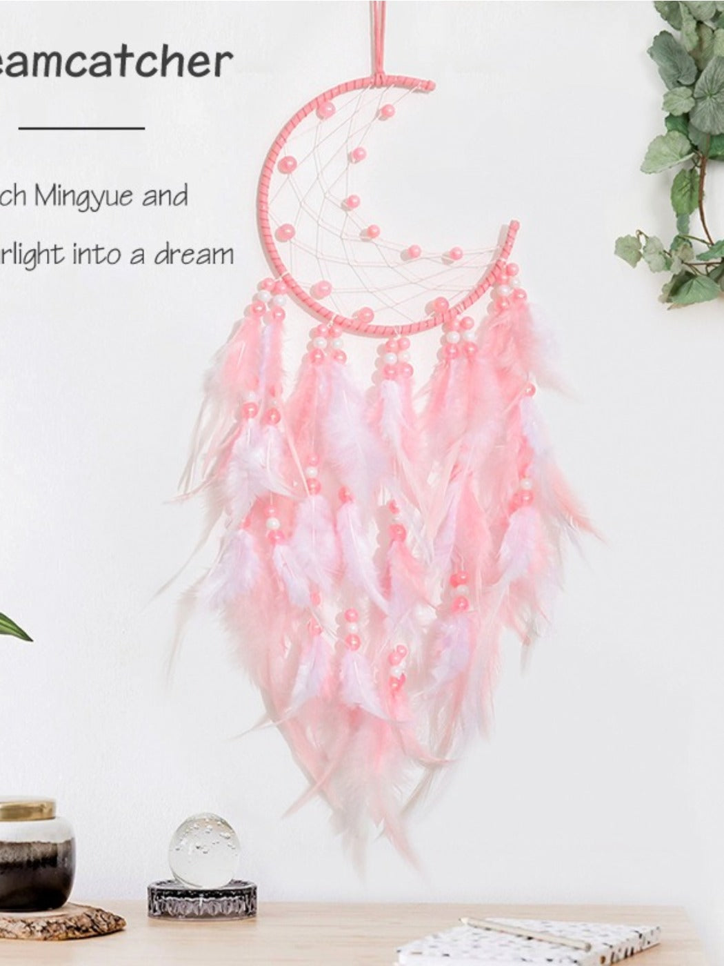 Pink feather ornament attached to the bottom of the moon shaped dream catcher