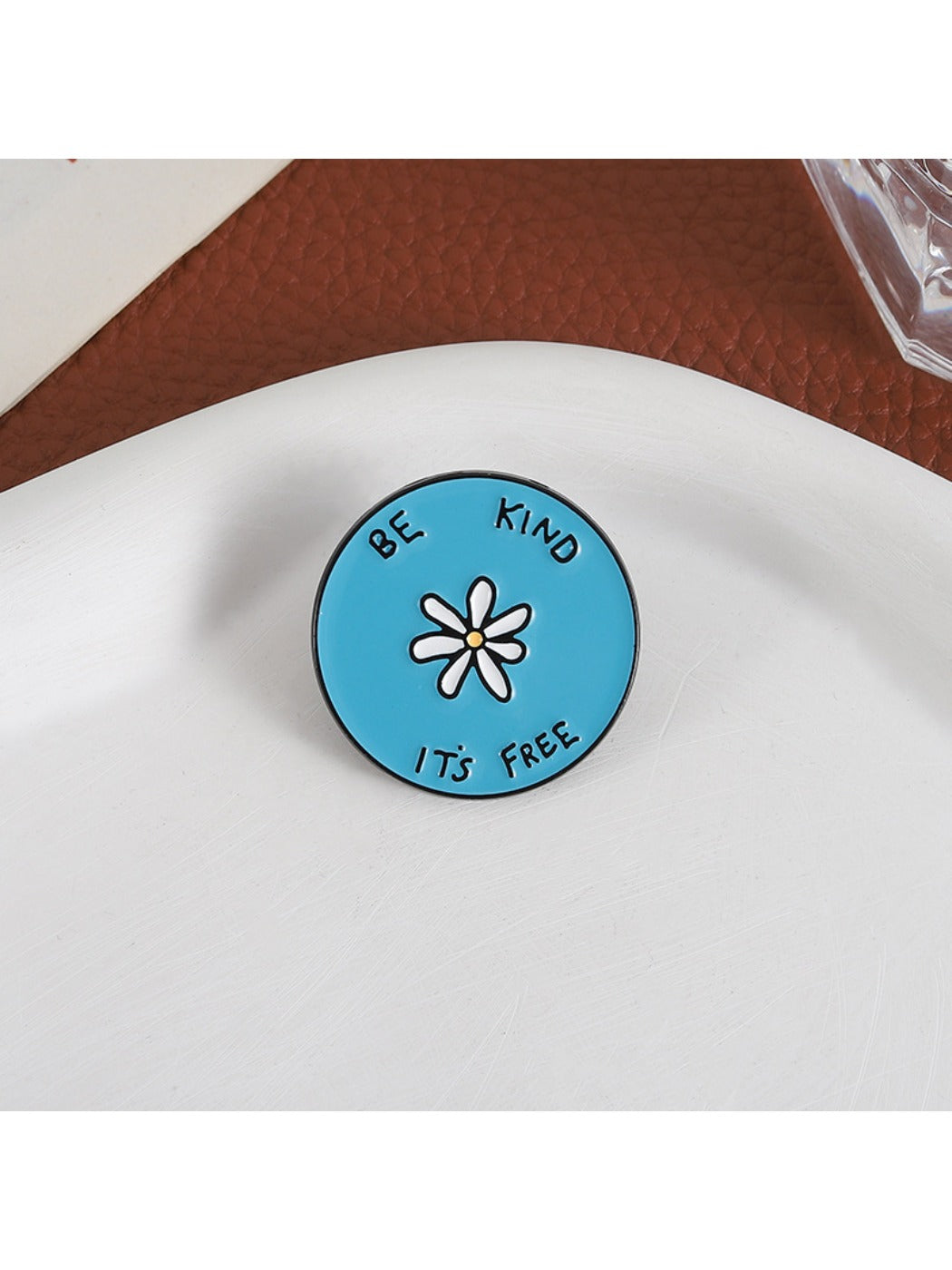 Side view of Pinori white flower alphabet blue round brooch showing thickness