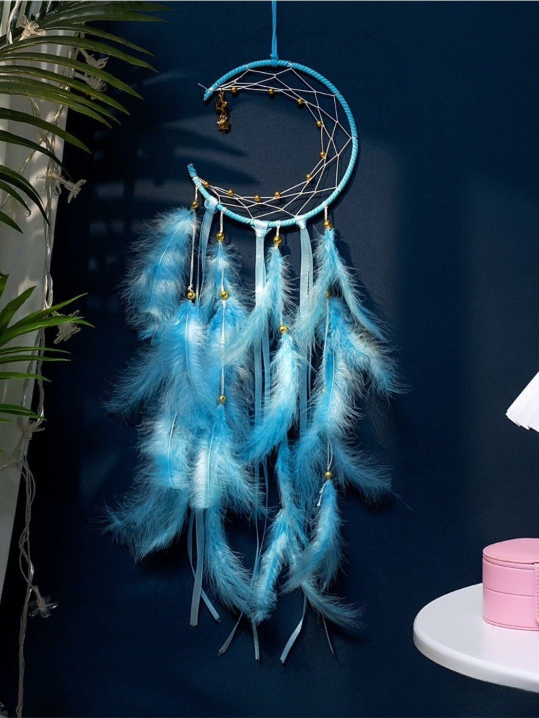 Close-up of the crescent moon frame with intricate webbing and hanging feathers on the wind chime