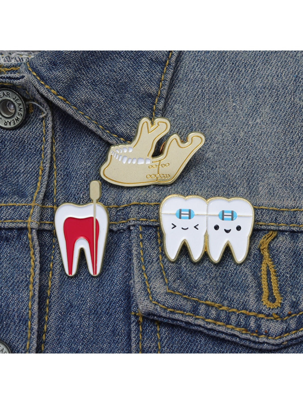 Pinori dental brooch displayed on a black fabric surface highlighting tooth shape