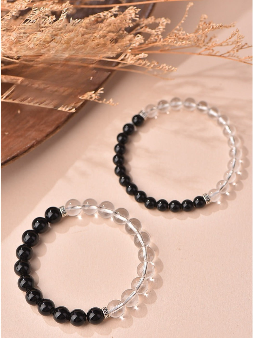 Emora bracelet worn on wrist featuring white and black beads with elastic band