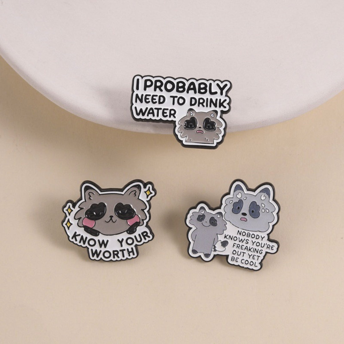 Close-up of Pinori Positive Raccoon Quote enamel pin with raccoon and motivational text