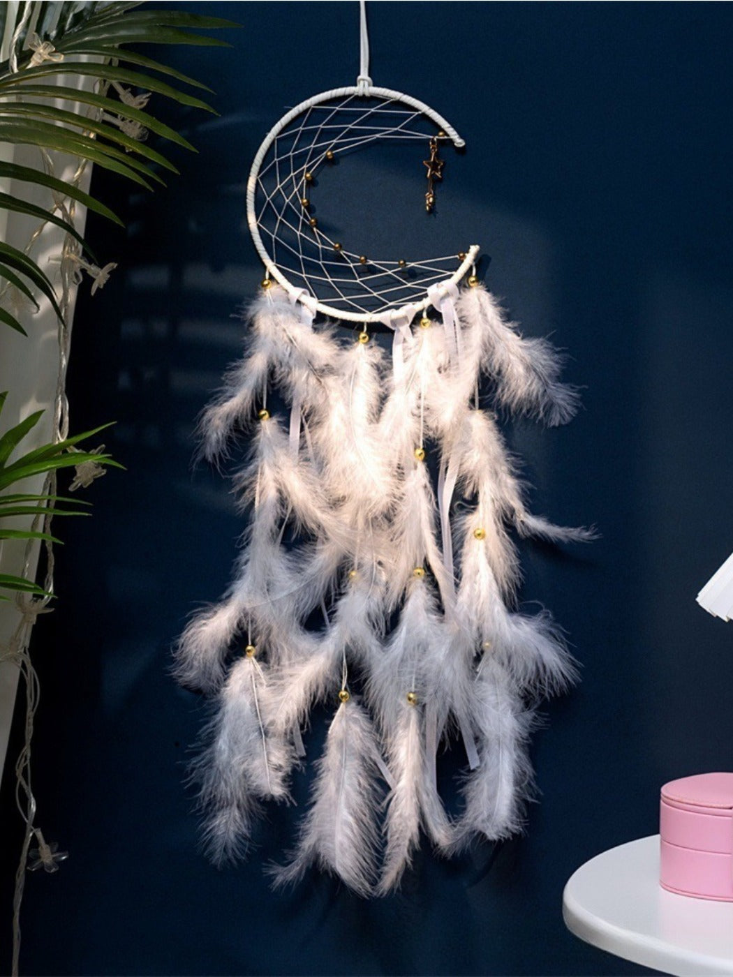 Somnira moon-shaped dreamcatcher wind chime with feathers and beads hanging on a wall