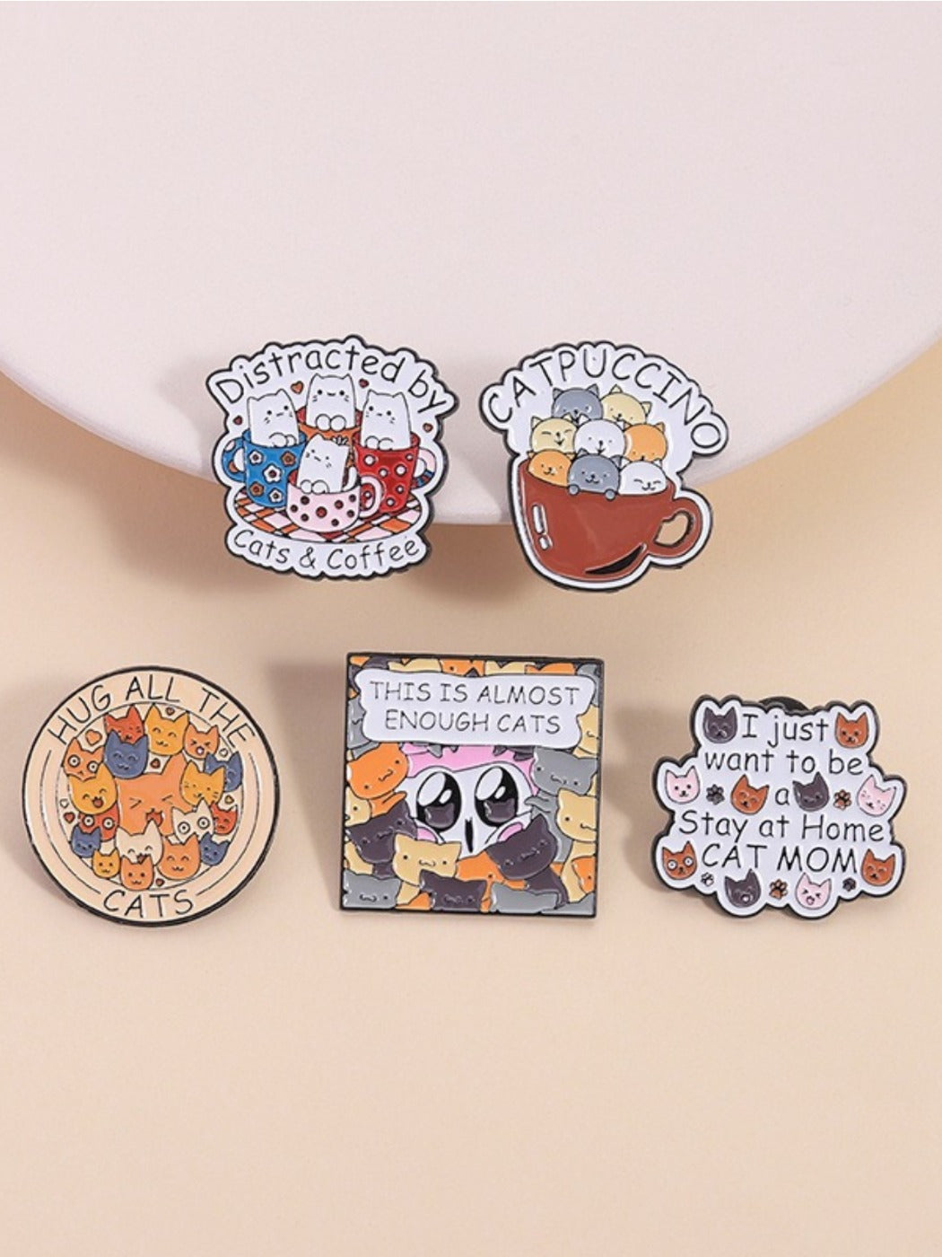 Round metal pin featuring a funny stacking cat design with vibrant colors