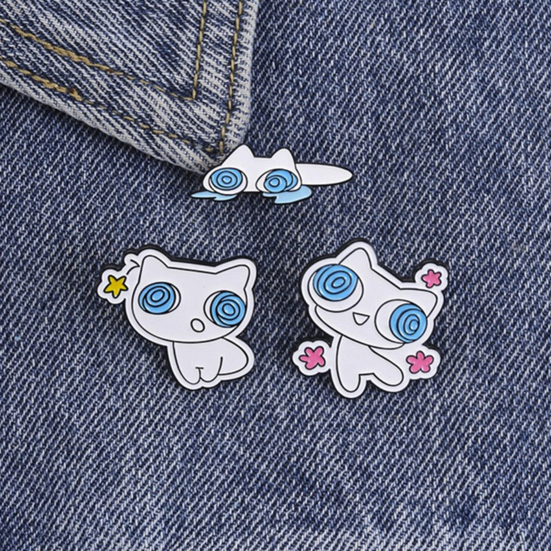 Pinori Dizzy Eye White Cat enamel pin held in hand for size reference