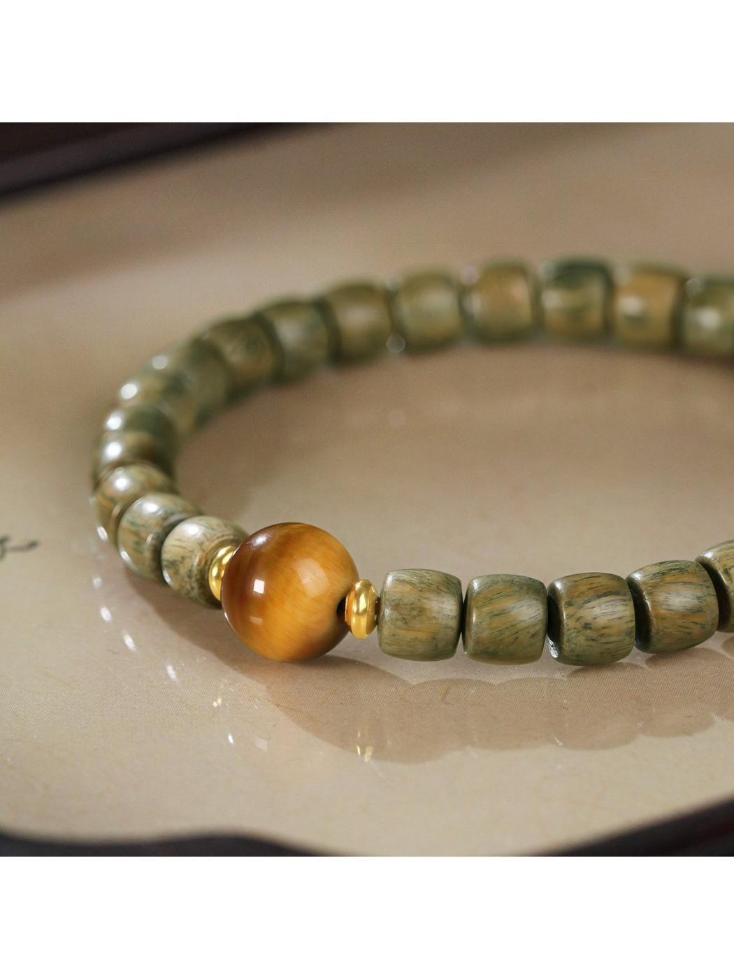 Emora bracelet worn on wrist featuring green sandalwood beads and cat eye stone