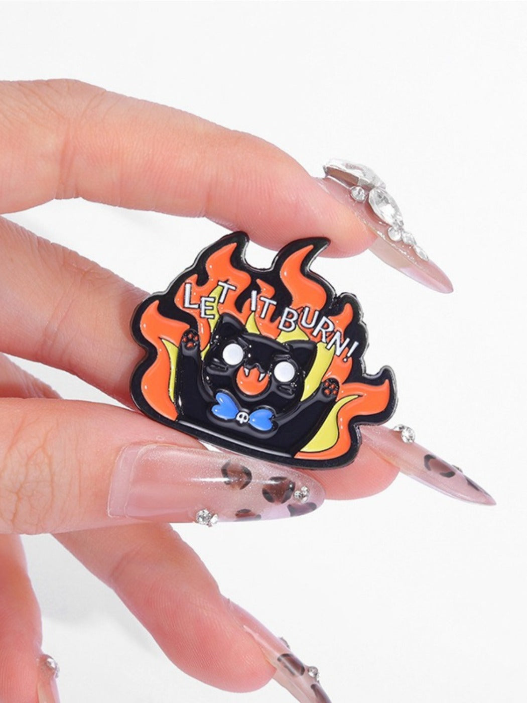 Pinori Evil Kitten brooch pinned on black fabric displaying colorful flame pattern