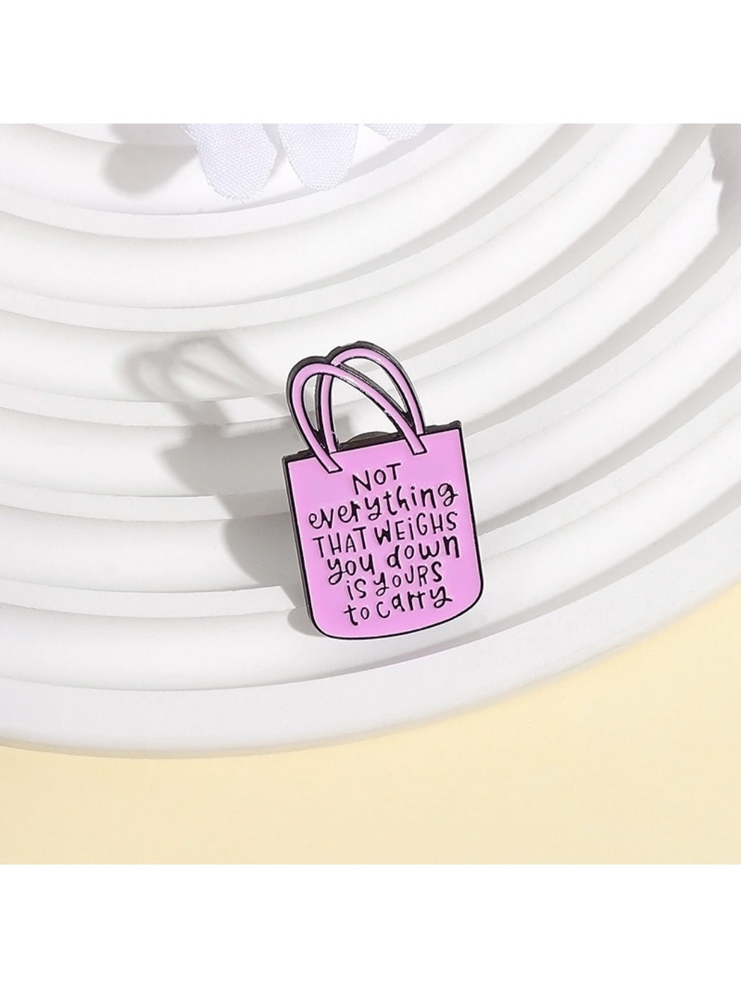 Pinori pink tote bag brooch displayed on a black fabric background