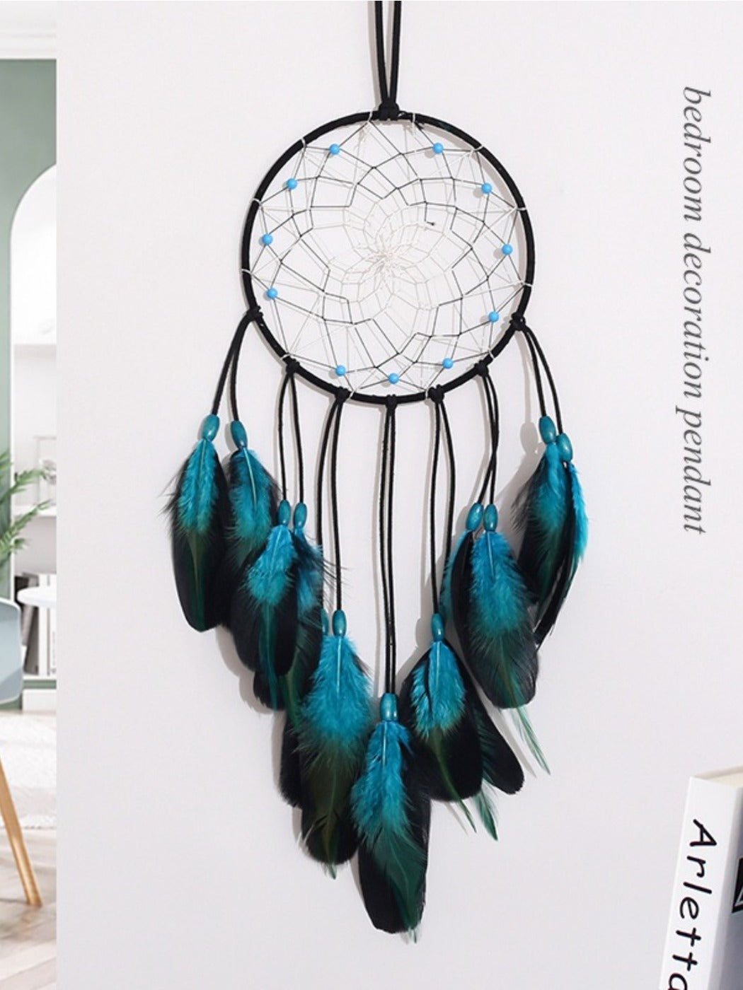 Dreamcatcher hanging on white wall with blue feathers and natural wood hoop
