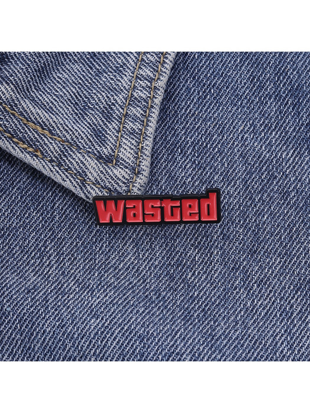 Hand holding the Pinori 'Wasted' text pin showing its size and detail