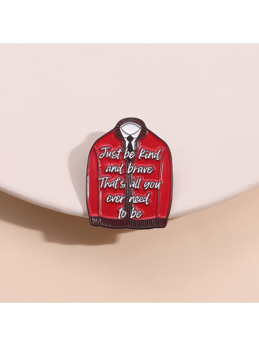 Close-up of Pinori red fashion pin with inspirational text on white background