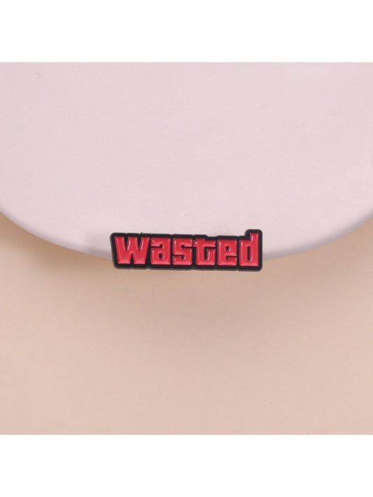 Close-up of Pinori 'Wasted' text pin with black and white design on a white background