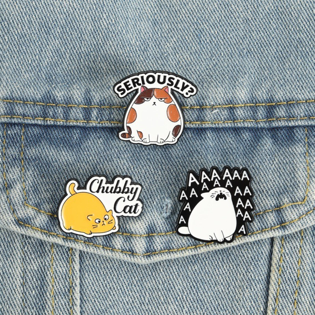 Pinori chubby cat mood enamel pin held in hand showing size and detail