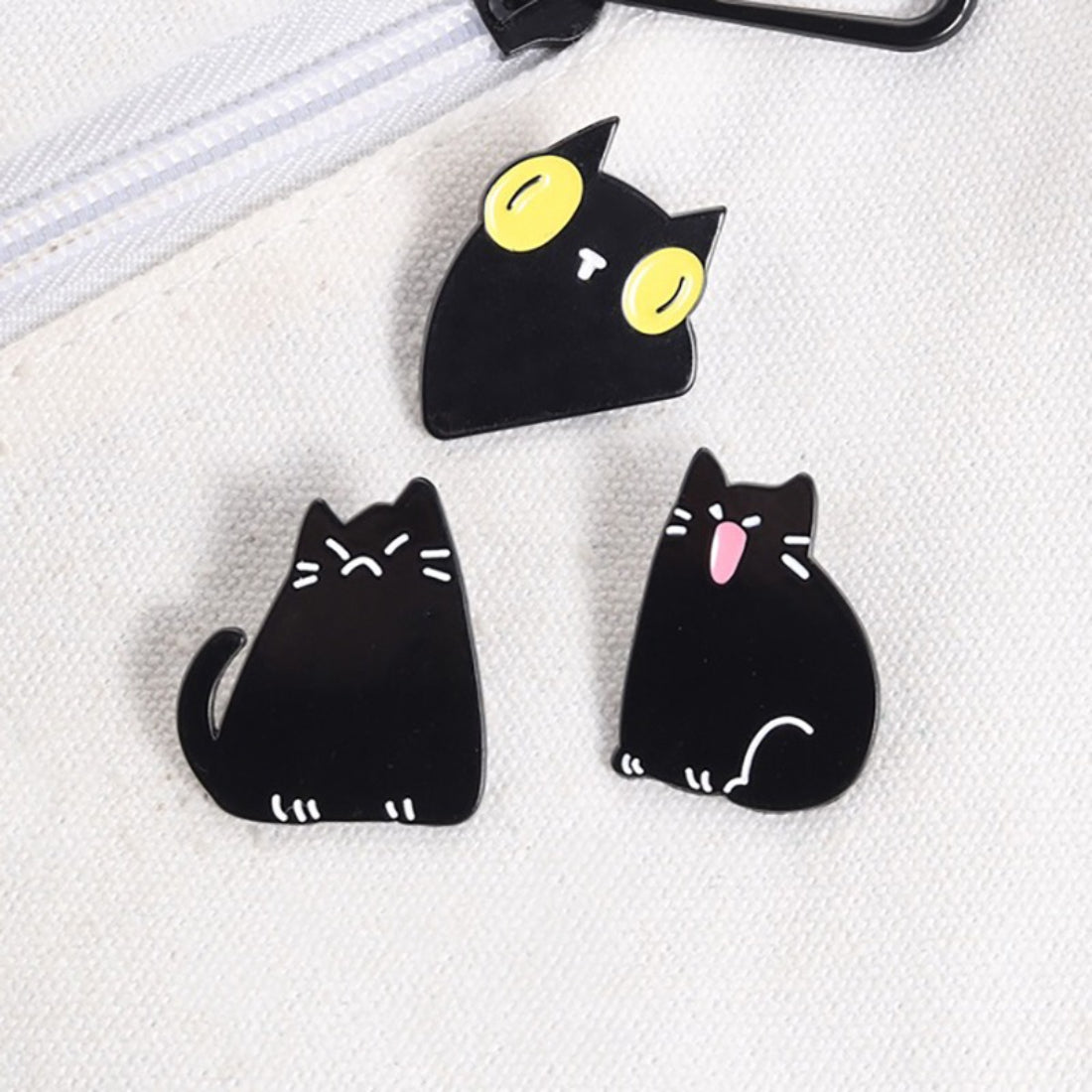 Pinori black cat enamel pin displayed on a denim jacket pocket