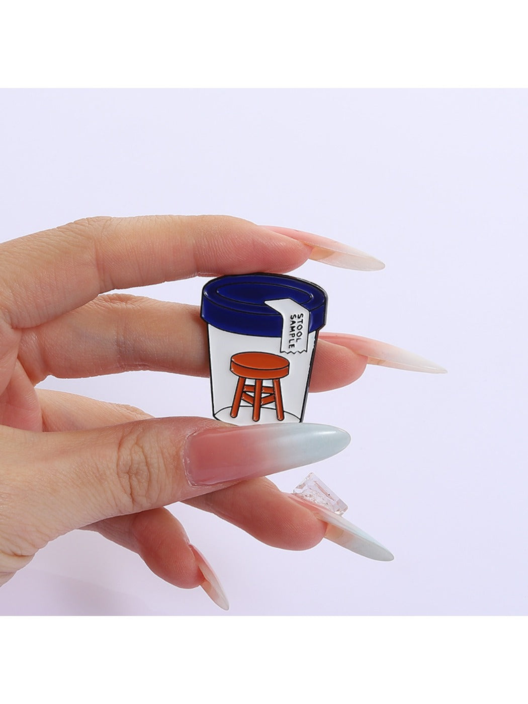 Pinori stool sample bottle pin badge attached to denim fabric