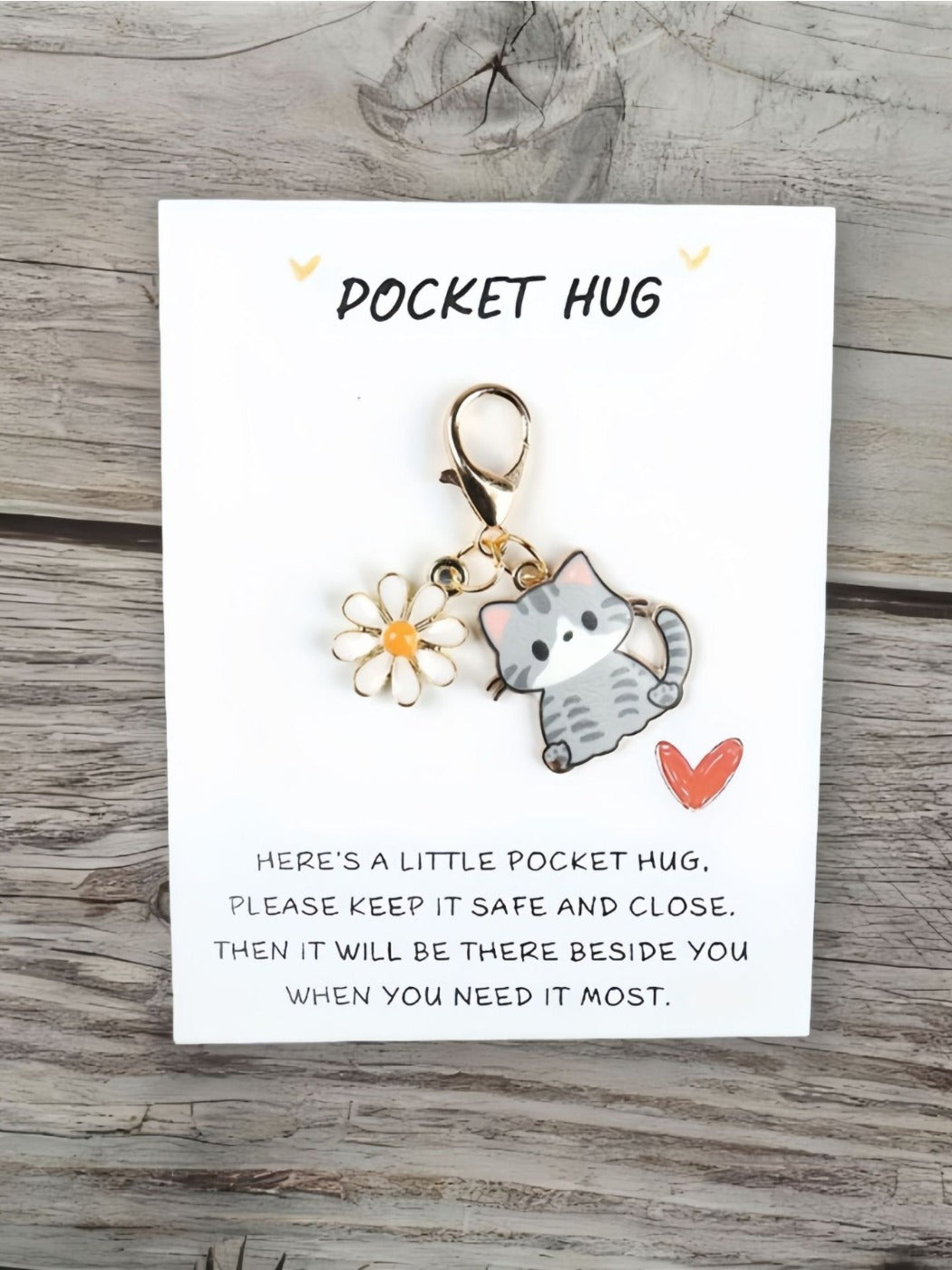 Taphug Pocket Hug keychain with cartoon cat charm placed on a fabric background
