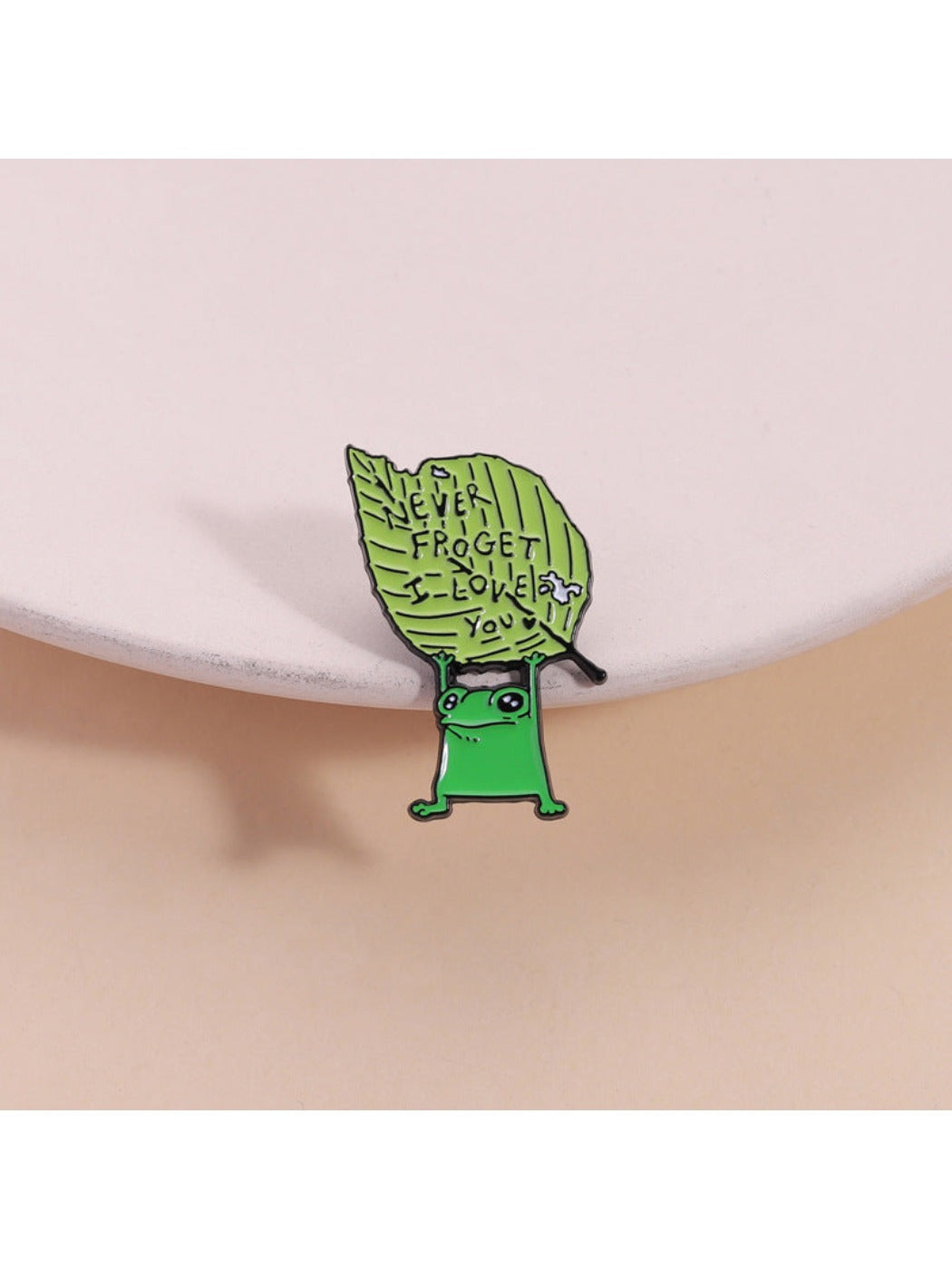 Pinori cute frog brooch with a green leaf detail on white background