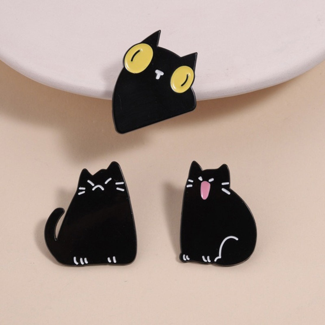 Close-up of Pinori black cat mood enamel pin with funny expression on white background
