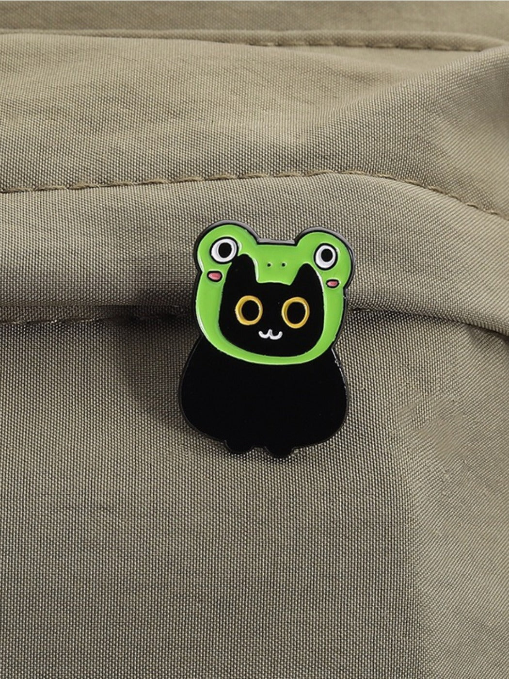 Pinori frog brooch with yellow eyes attached to a denim jacket