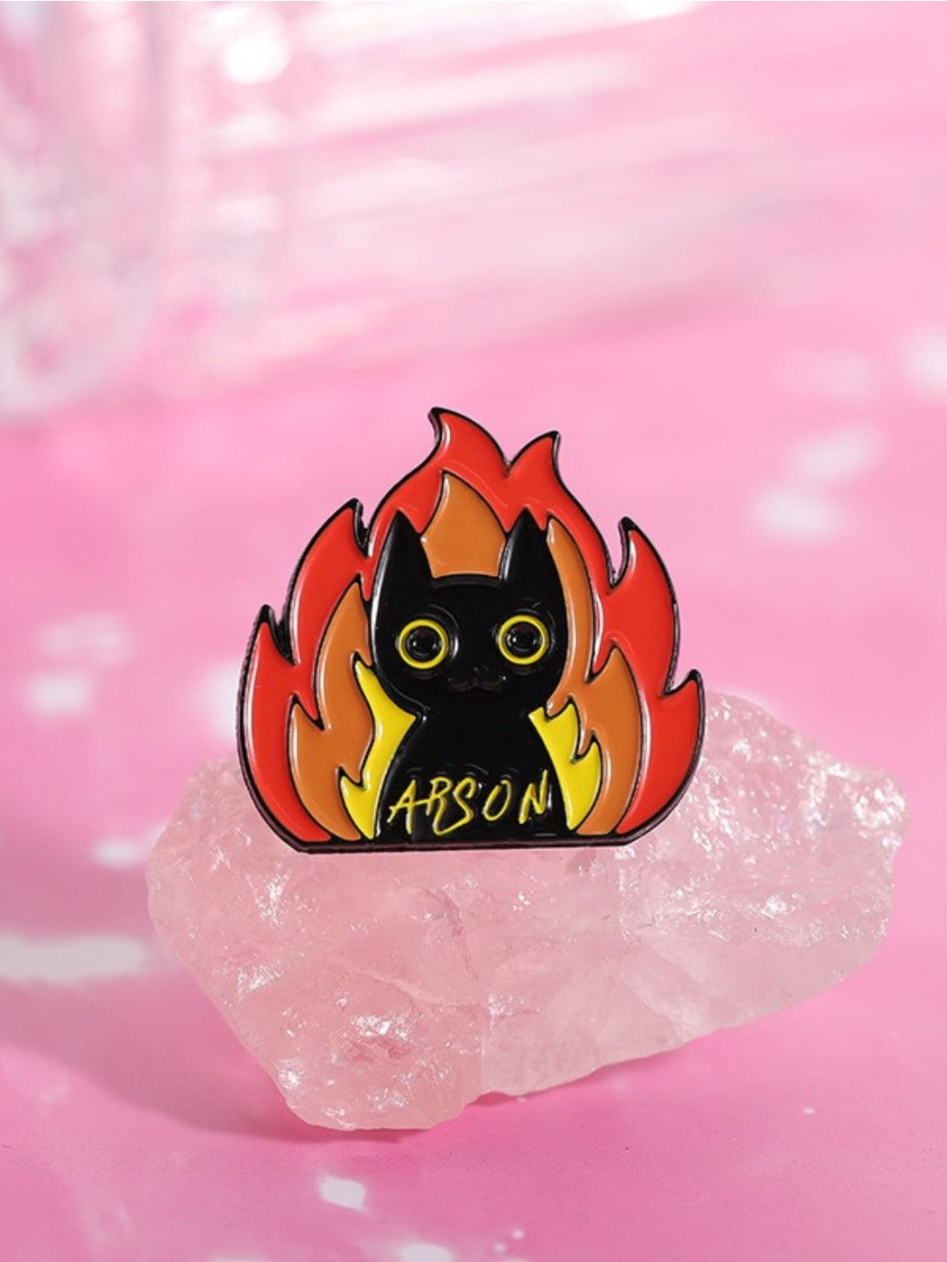Pinori black cat badge pinned to a backpack with flames around