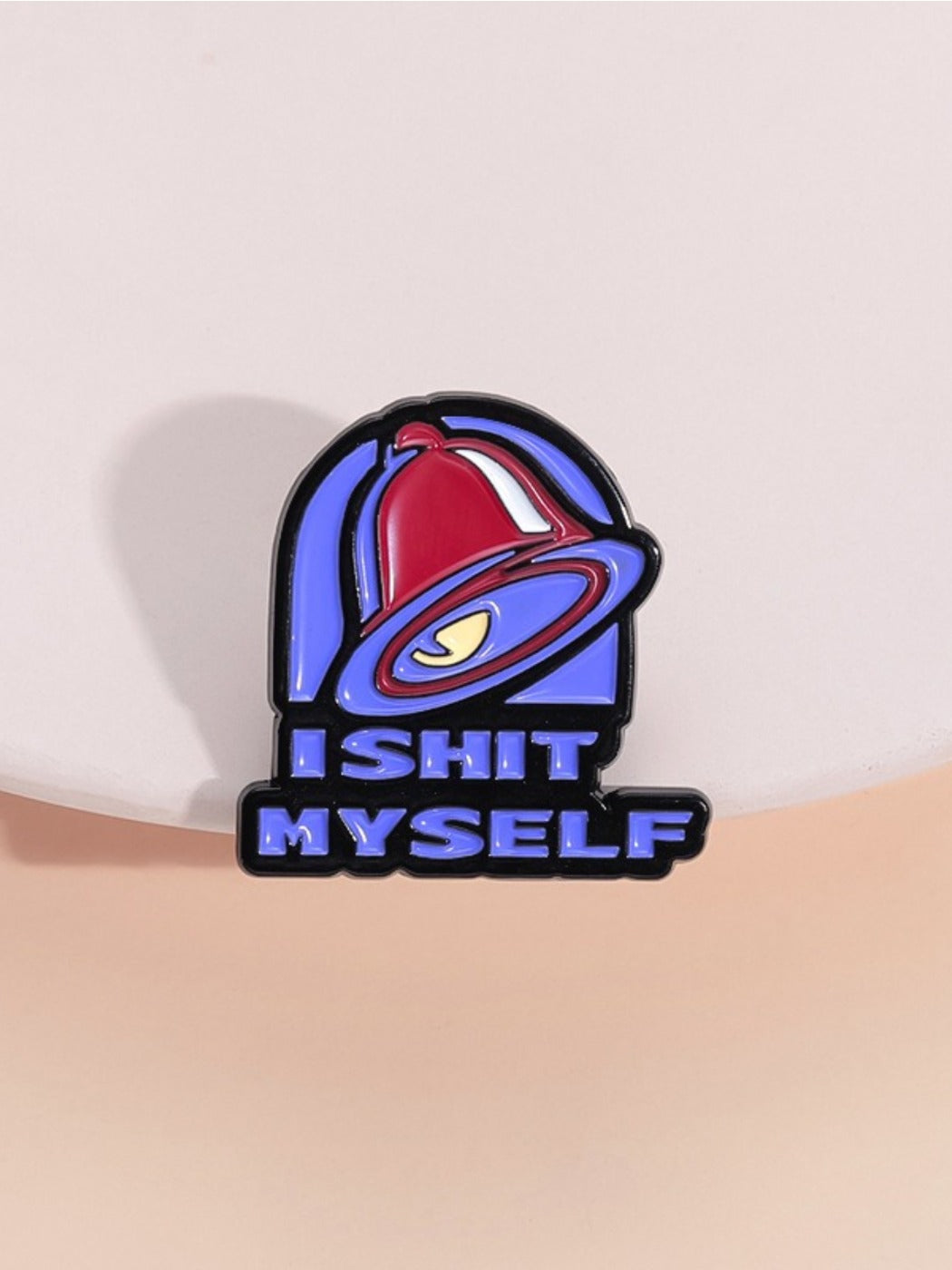 Close-up of Pinori purple dog bell brooch with metal badge on white background