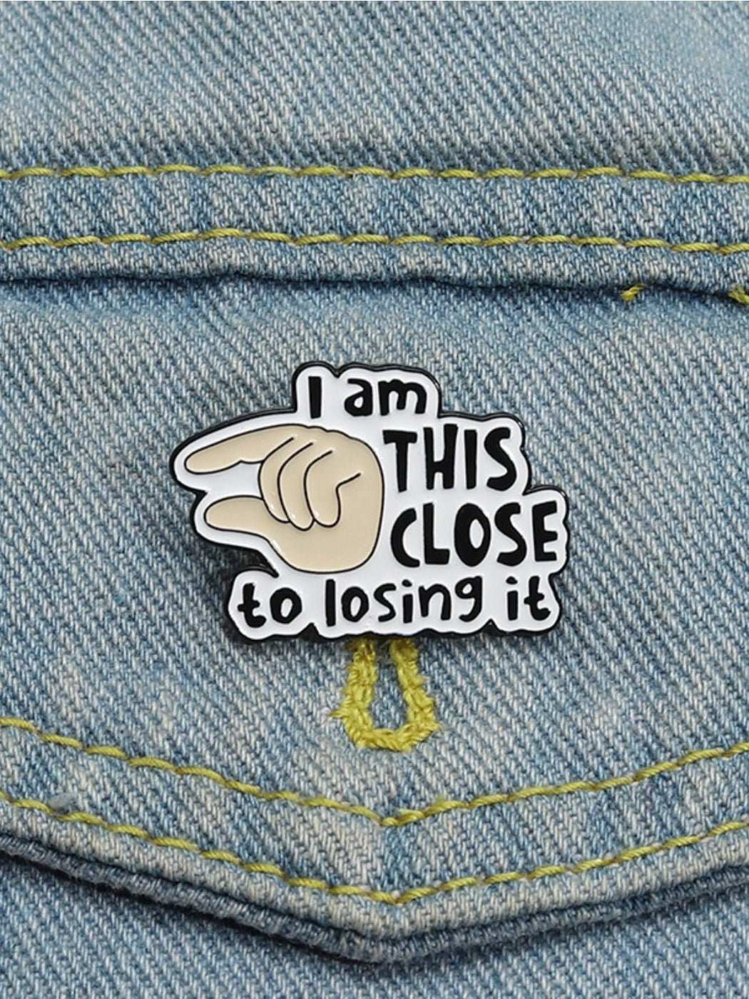 Pinori pin badge held between fingers showing size and design details
