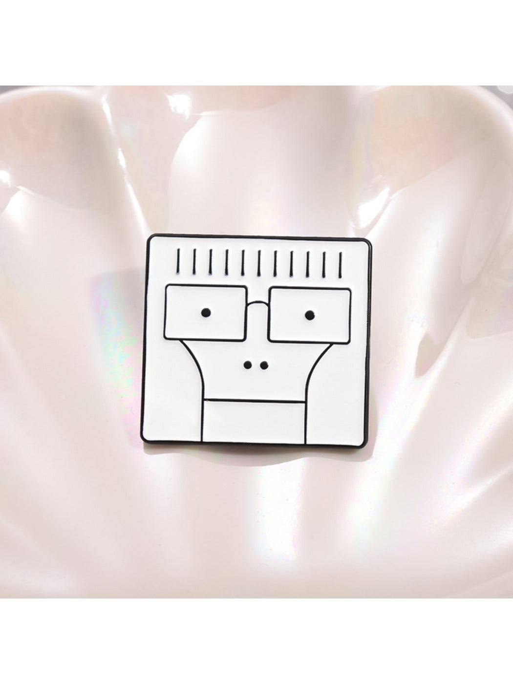 White enamel pin with simple cartoon face design pinned on a backpack