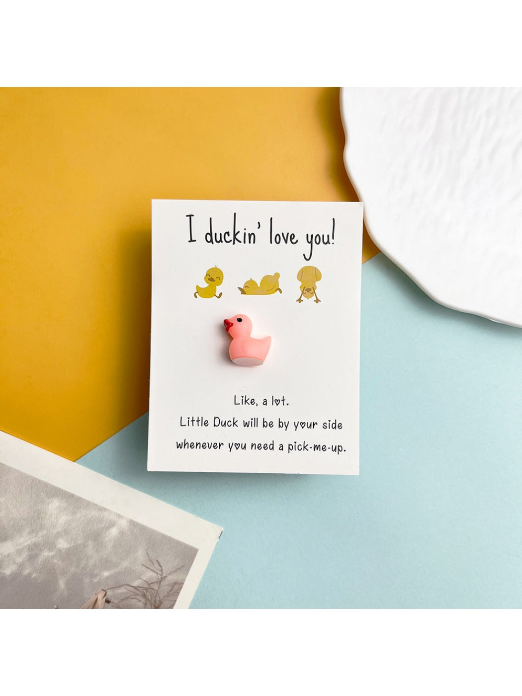 Yellow resin duck inside the pocket hug card with a soft shadow background