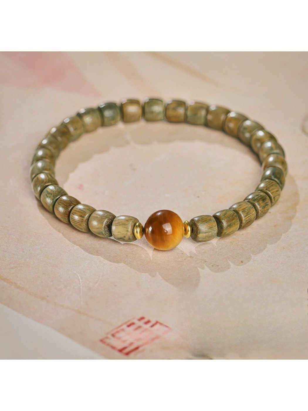 Emora bracelet showing round green sandalwood beads and polished cat eye stone