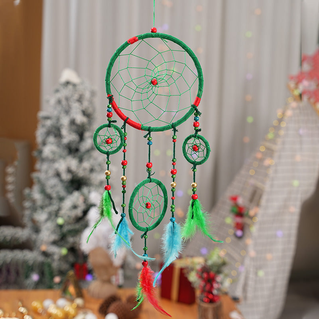 Green dreamcatcher with red accents and suspended feather-look elements in a decorated room