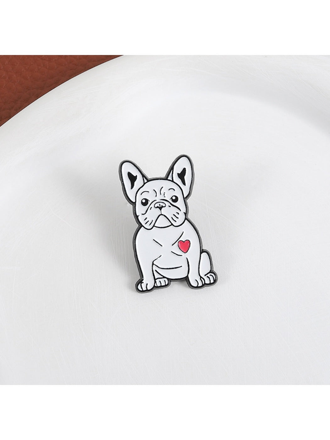 Pinori cartoon pug brooch displayed on a fabric surface highlighting its size and shape