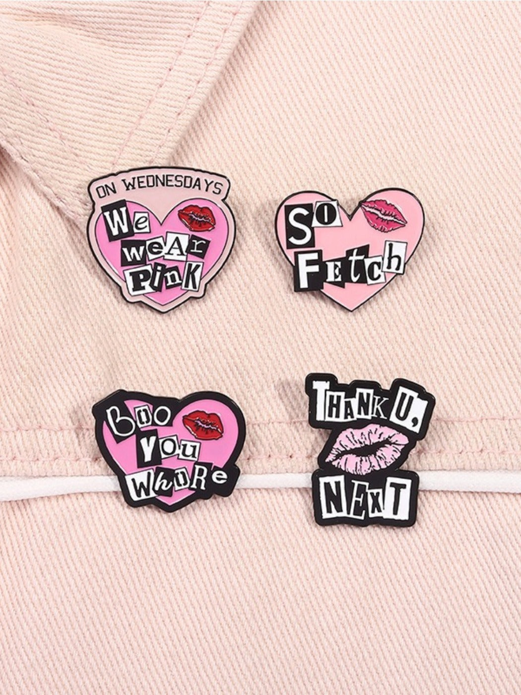 Pink heart shaped metal pin with punk alphabet design displayed on corkboard