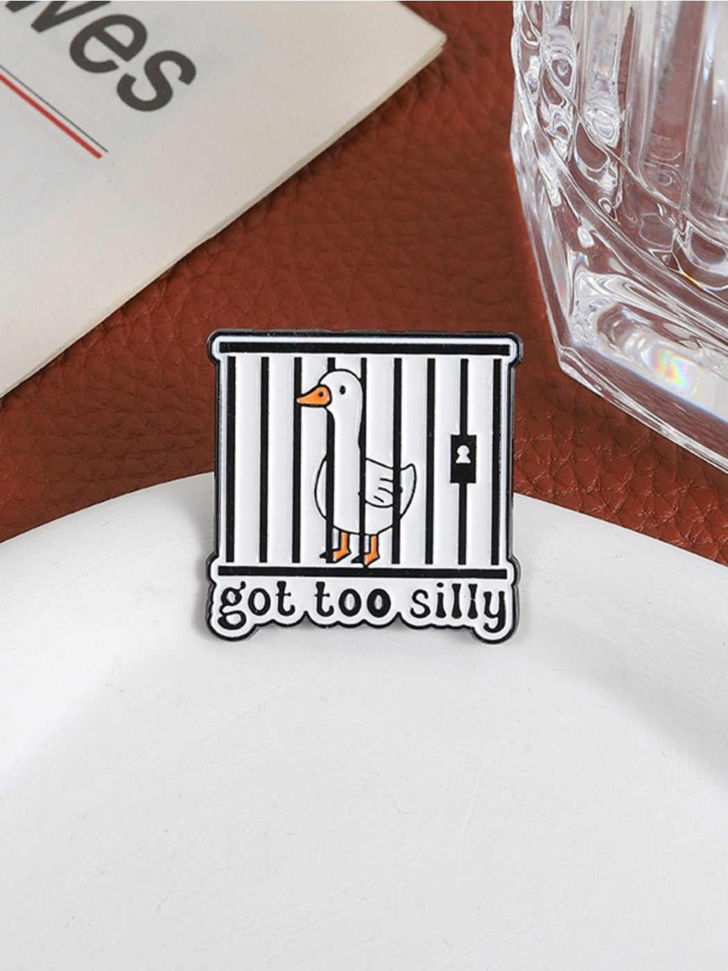 Pinori cute animal silly goose enamel pin displayed on a black fabric surface