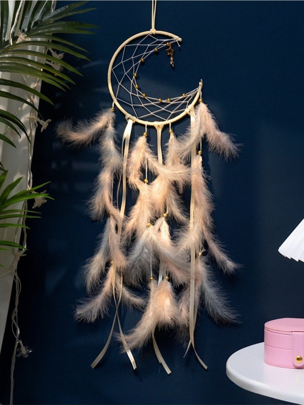 Somnira wind chime hanging outdoors with sunlight highlighting the feathers and beads