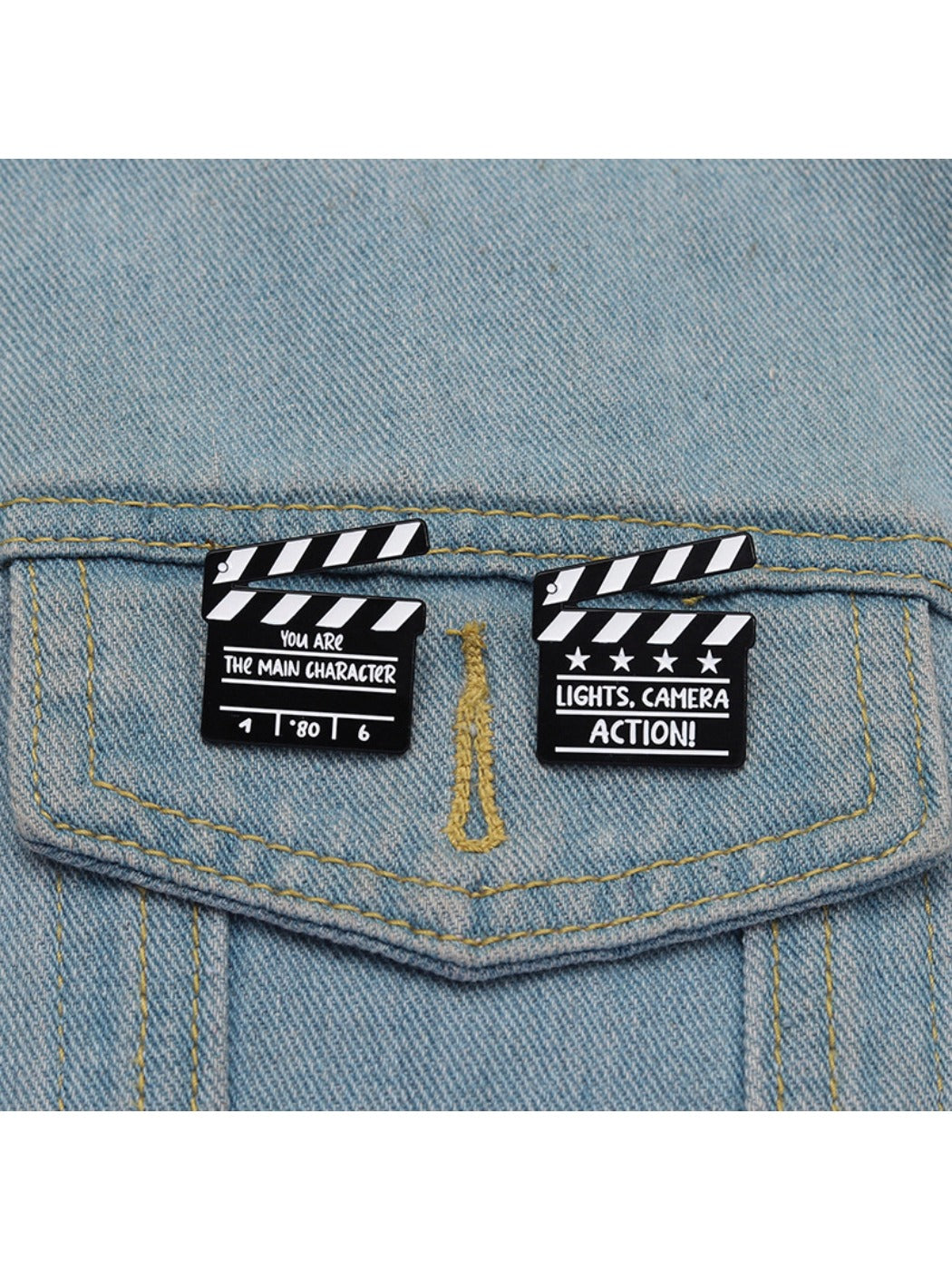Pinori clapperboard brooch displayed on a black fabric surface