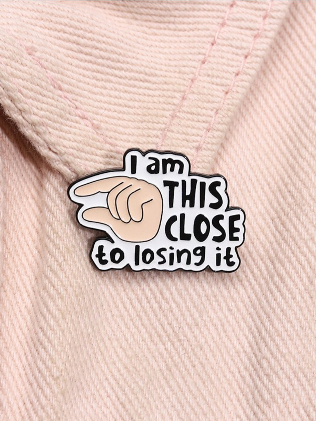 Pinori brooch attached to fabric, displaying 'I Will Close It' text and finger graphic