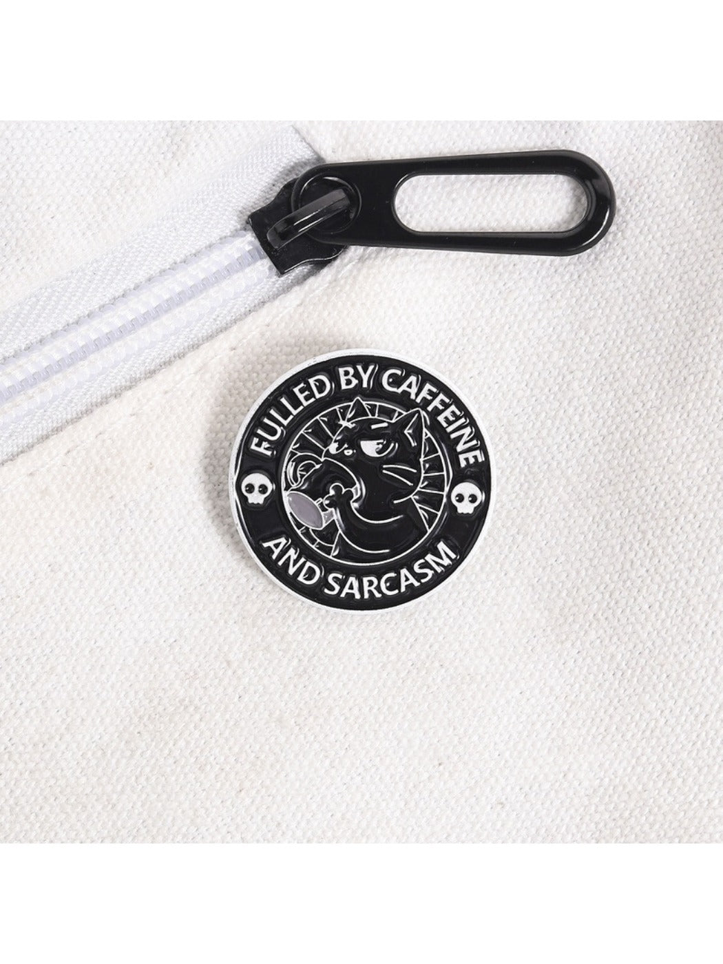 Pinori black coffee cat brooch pinned on a fabric surface