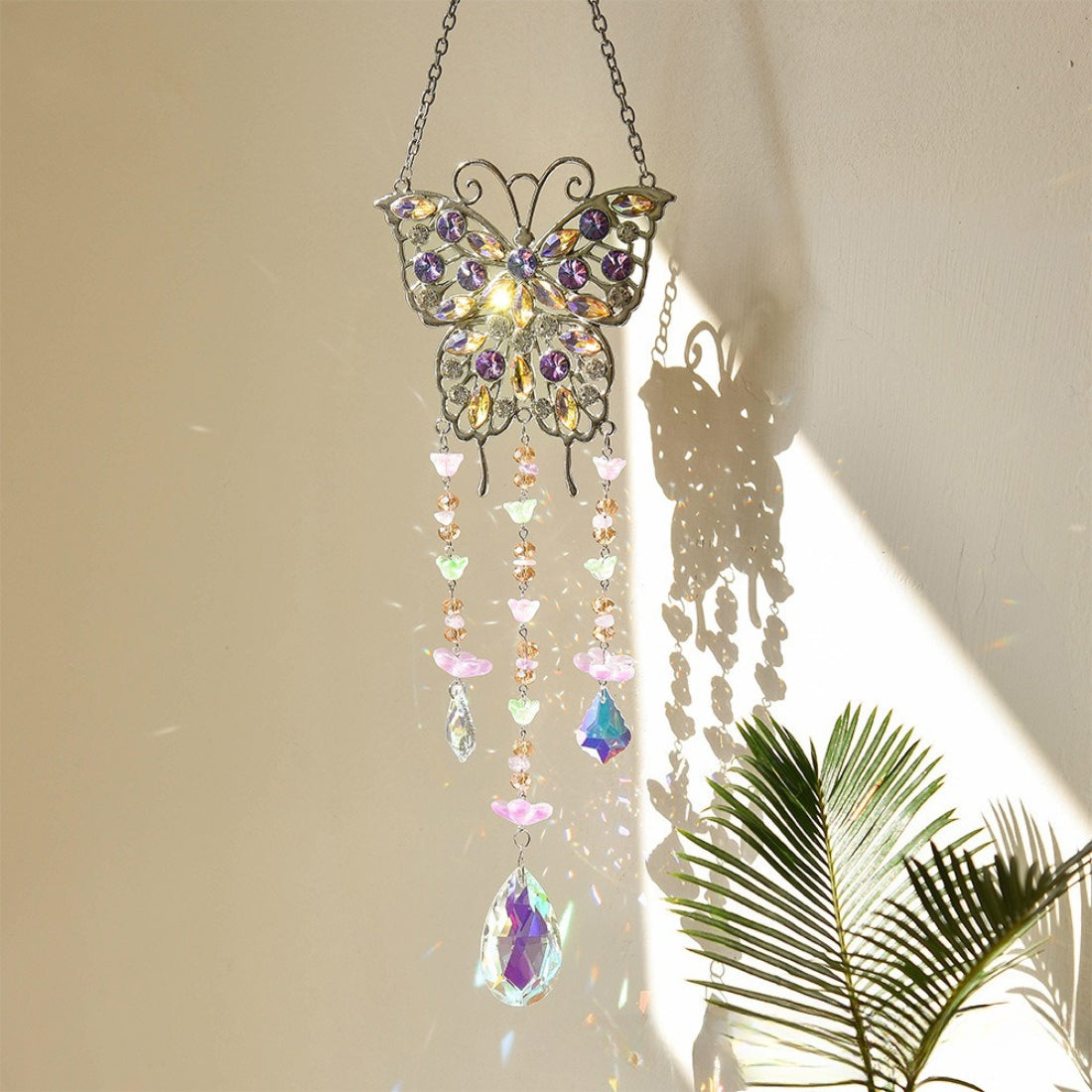 Somnira butterfly suncatcher hanging by a chain against a white background
