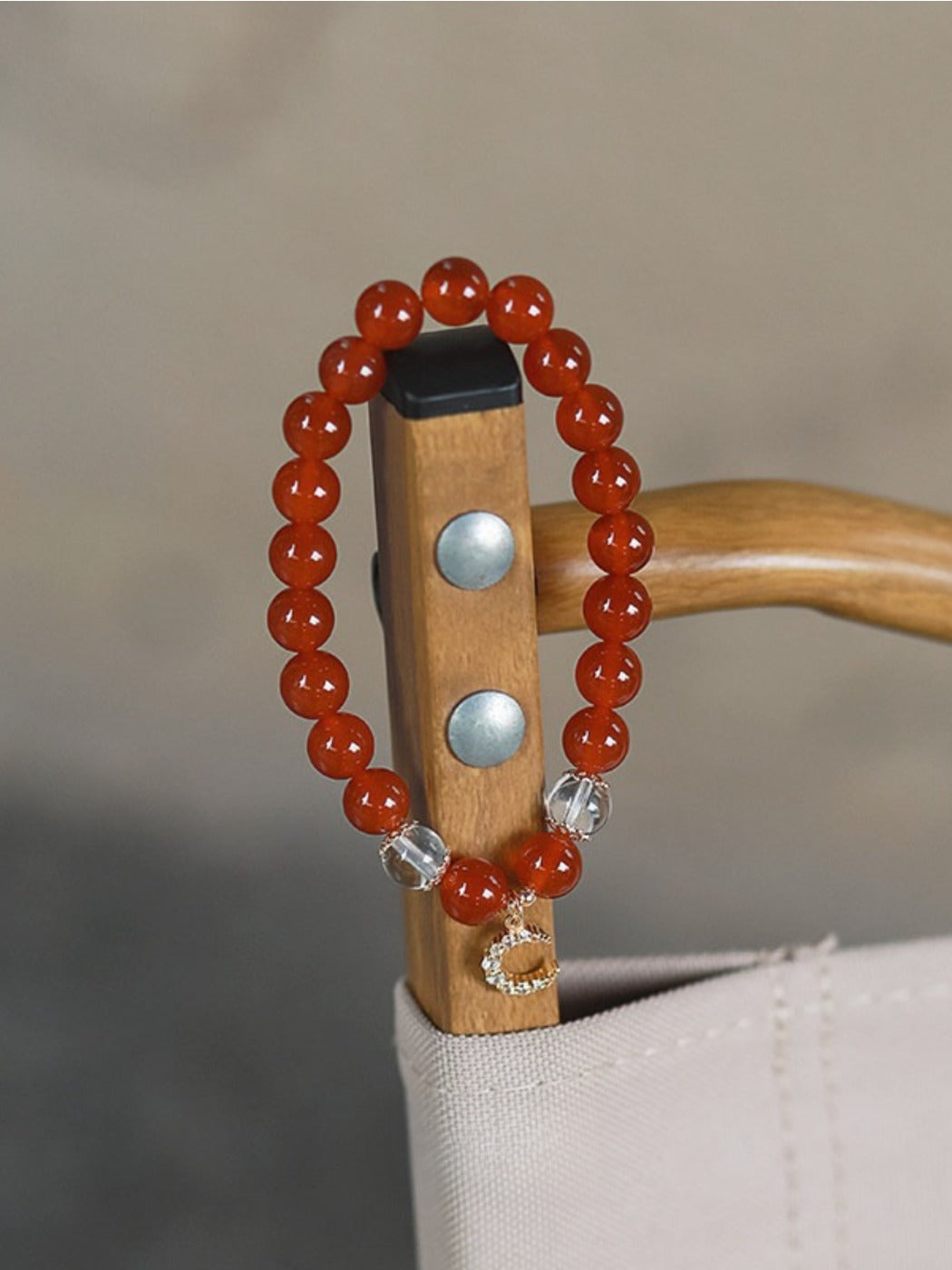 Close-up of Emora red agate bracelet with polished round beads on a white background